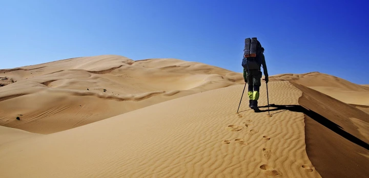 A hiker trekking through the dunes in the Namib desert