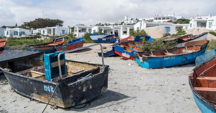 Múltiplos barcos de madeira em praia de Paternoster